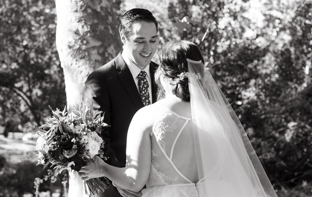 groom in navy suit and floral tie does first look with bride in tiered ballgown wedding dress at Temecula Creek Inn