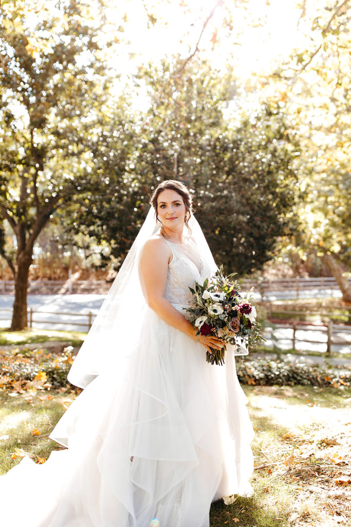 Outdoor wedding portrait shots at Temecula Creek Inn with bride in tiered ballgown wedding dress and red, blue and white bridal bouquet