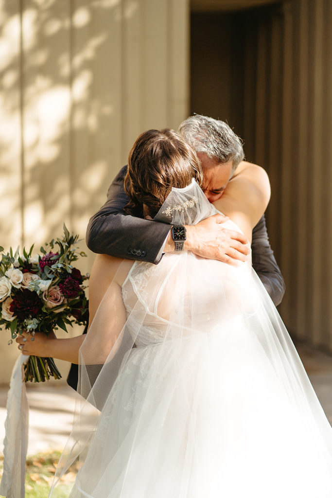 father of the bride hugs bride during emotional first look