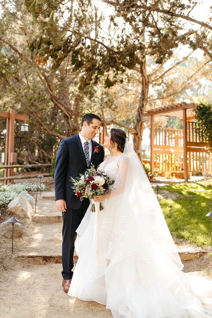 Outdoor wedding portrait shots at Temecula Creek Inn with groom in navy suit and floral tie and bride in tiered ballgown wedding dress