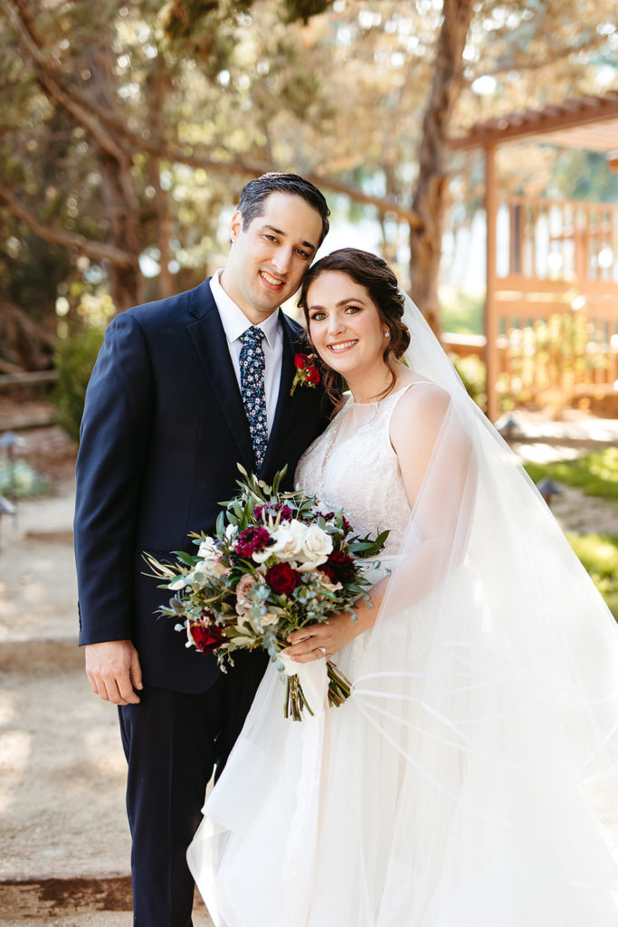 Outdoor wedding portrait shots at Temecula Creek Inn with groom in navy suit and floral tie and bride in tiered ballgown wedding dress