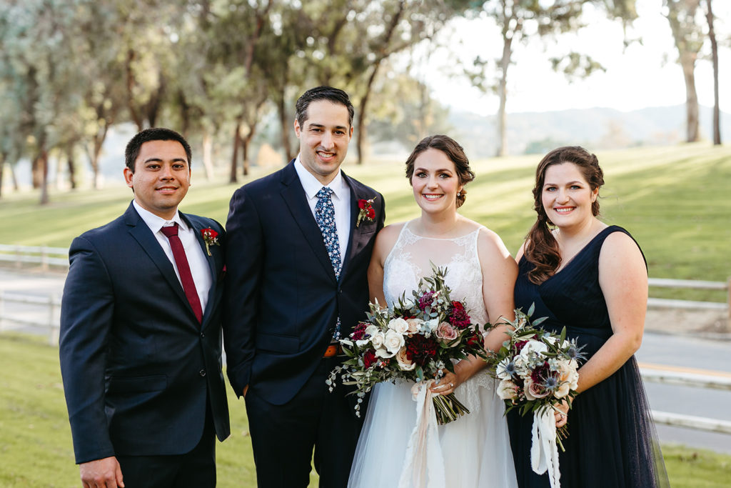 bride and groom stand with small wedding party in navy suit and dress