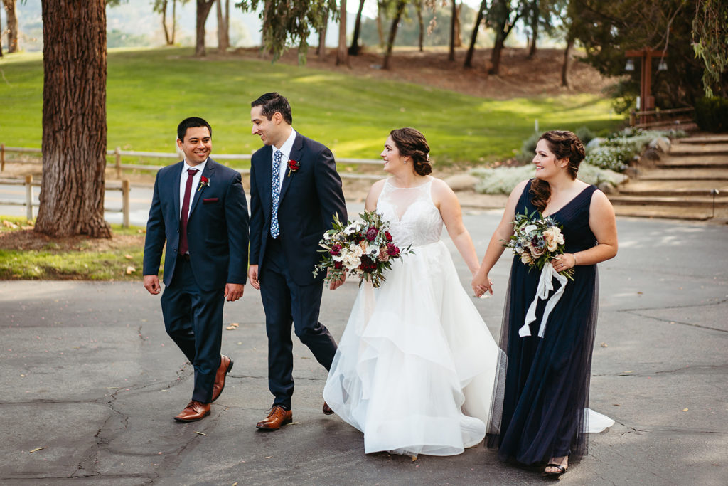 bride holds bridesmaids hand while walking 