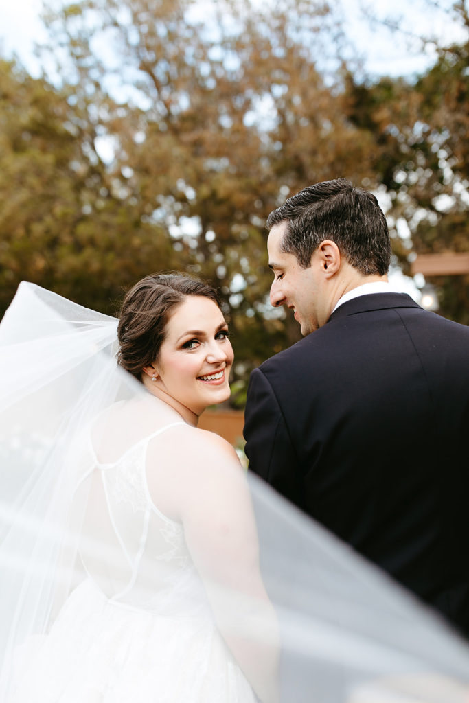 bride looks back at camera while veil wafts in the wind