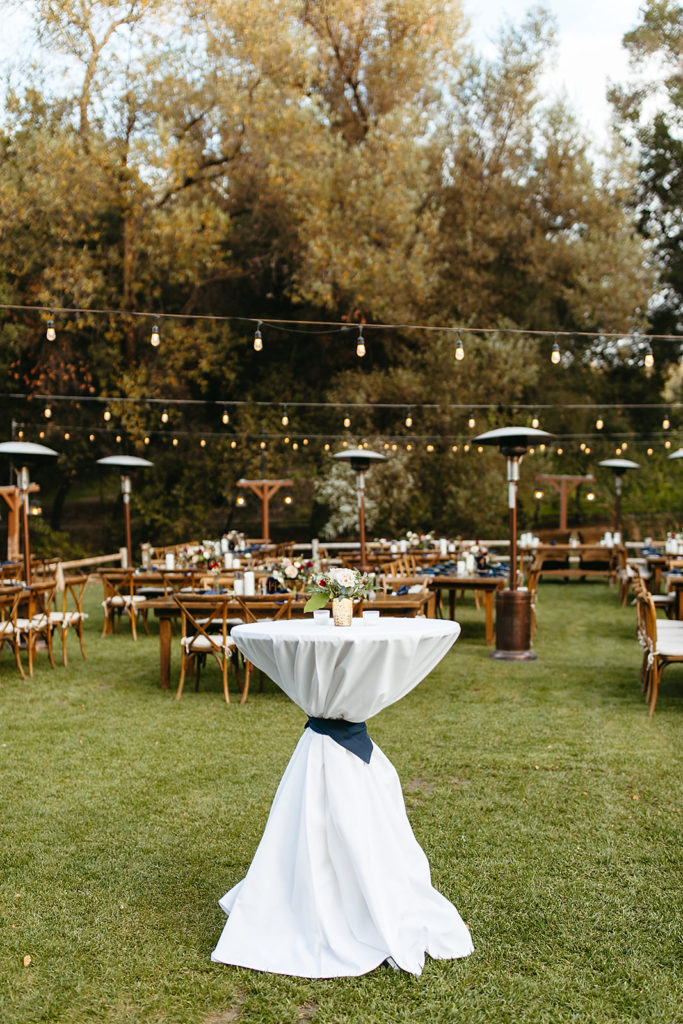 outdoor wedding reception at Temecula Creek Inn with wooden farmhouse tables, chairs and blue napkins with dark blue table numbers