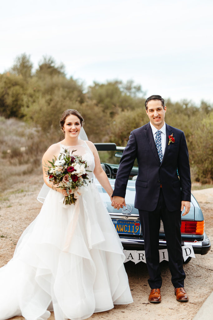 bride and groom stand by vintage blue Mercedes get away car with "just married" sign