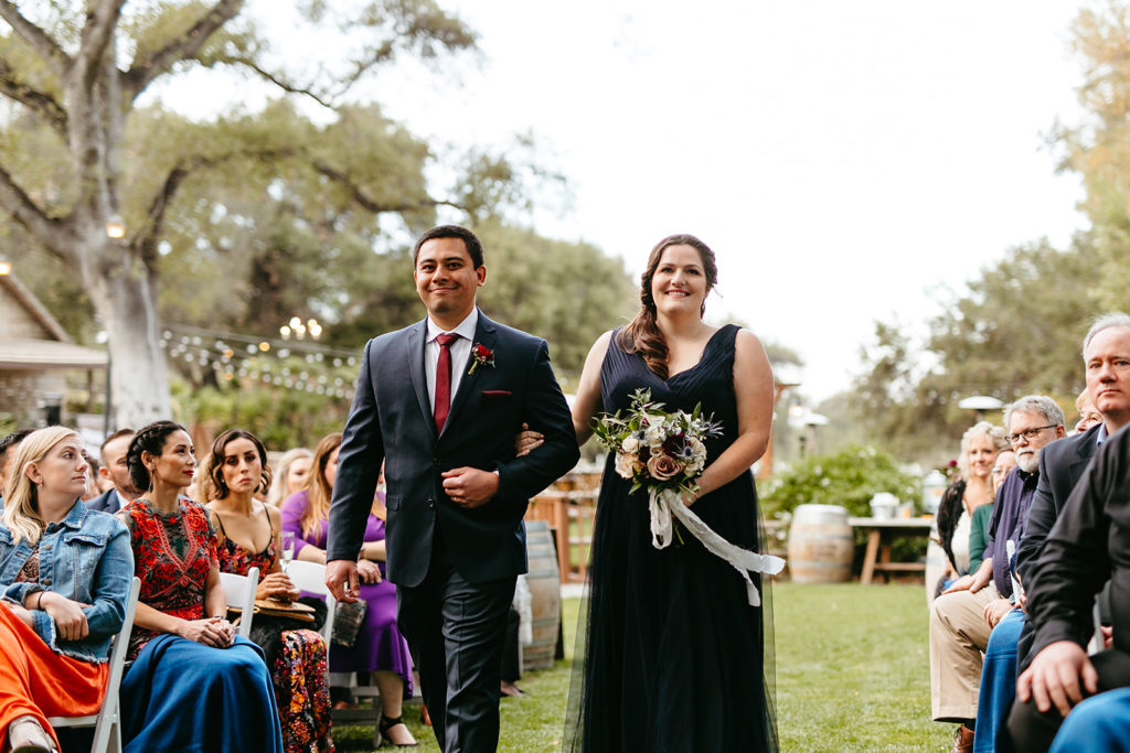 bridesmaid and groomsman in navy suit and dress walks down the aisle