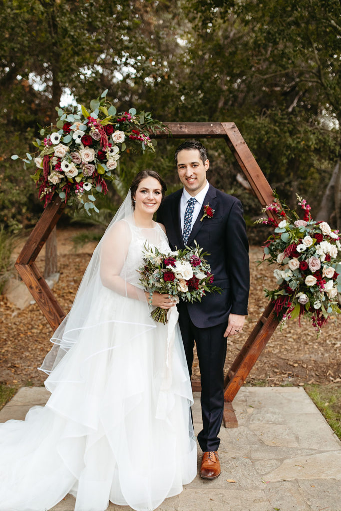 bride and groom portrait shot in front of wooden geometric ceremony arch