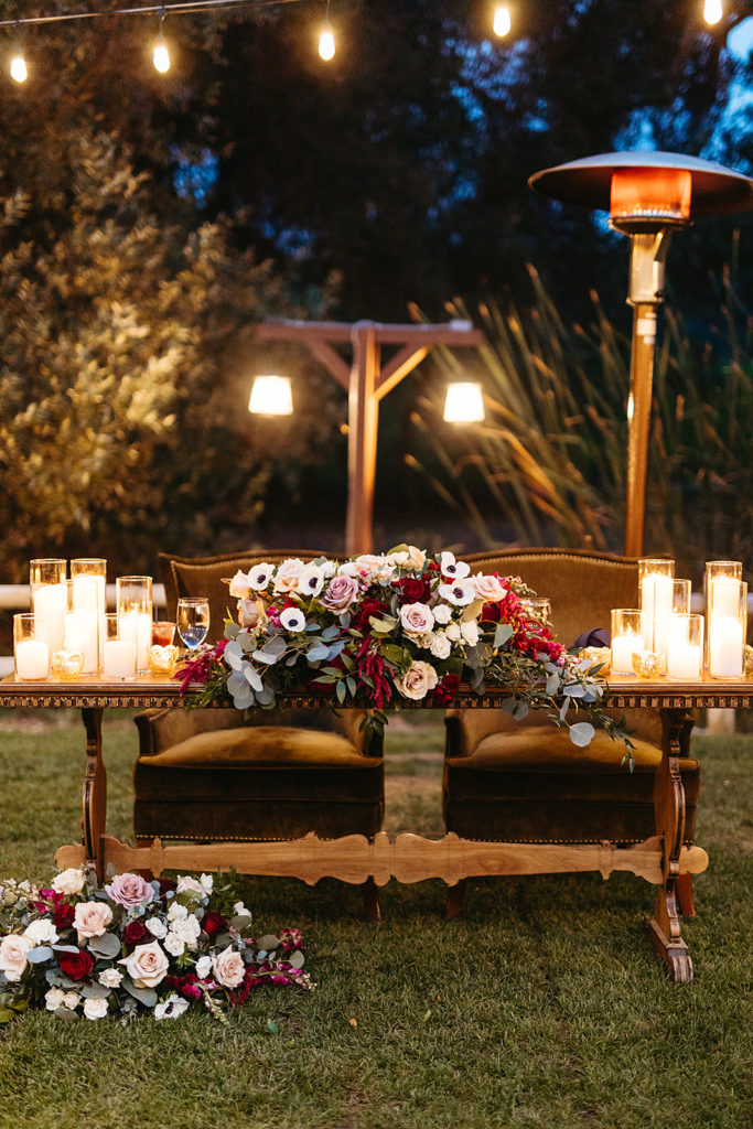 outdoor reception sweetheart table with floral red, white, green and blue arrangement