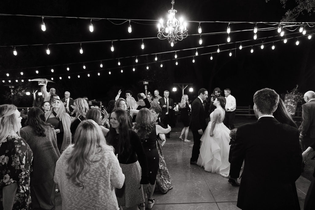 bride and groom surrounded by guests on dance floor during wedding reception 