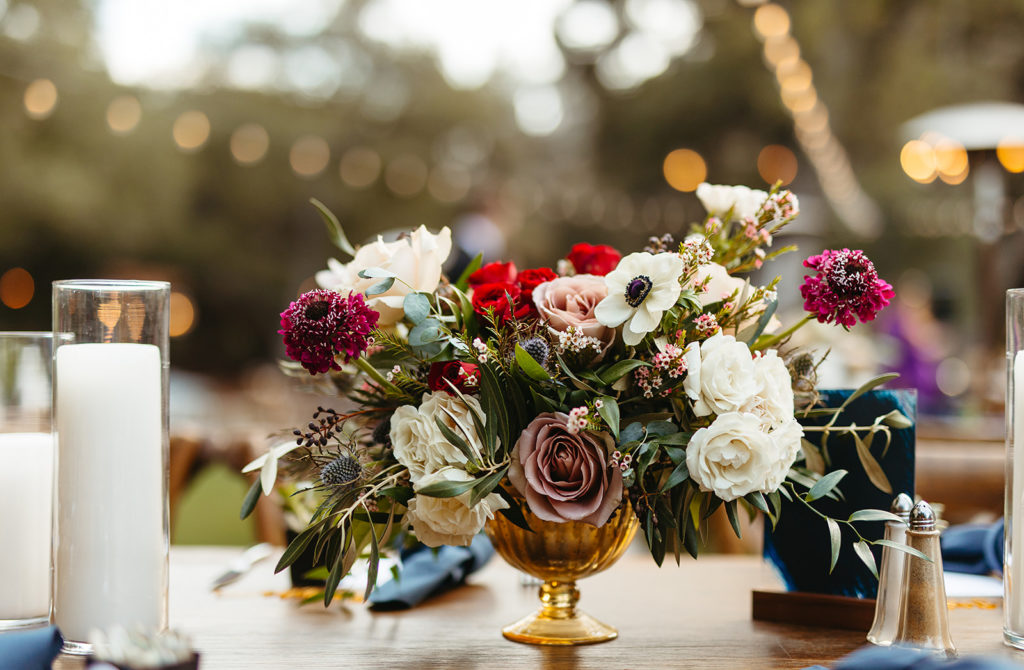 hygge wedding reception floral arrangement with red roses, sea holly, white anemone and eucalyptus