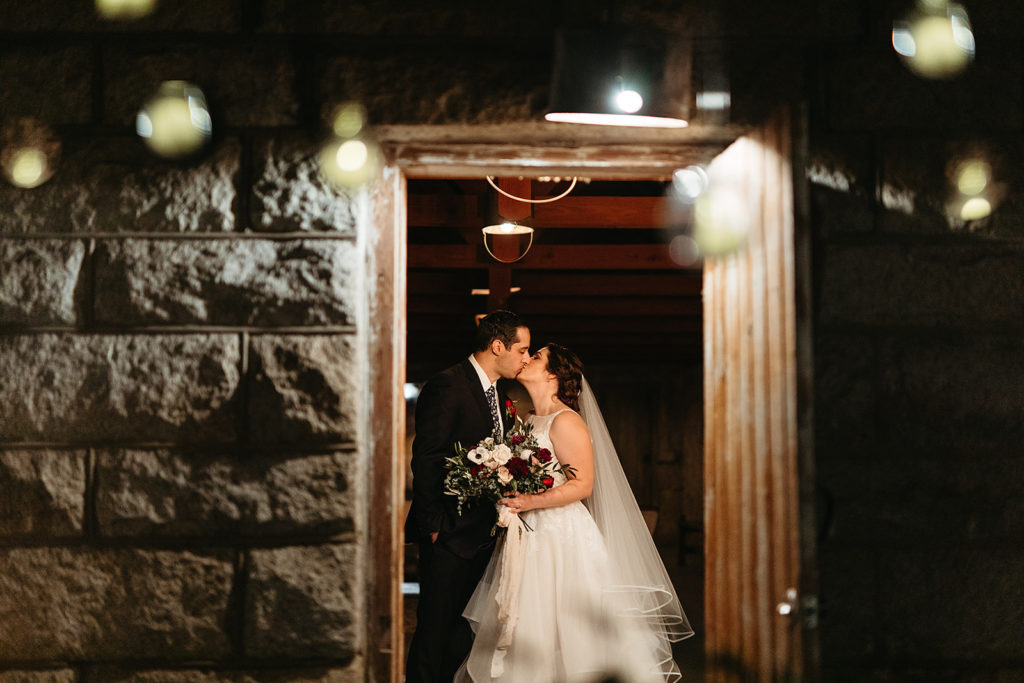 bride and groom kiss through barn door