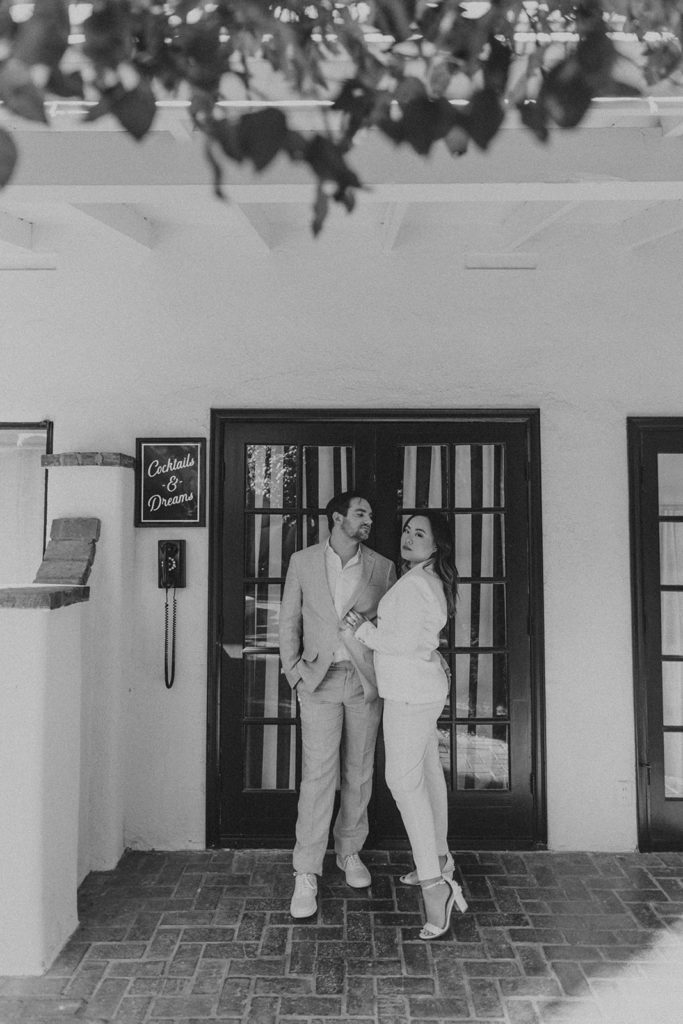 engaged couple wearing neutral matching power suits pose in mid century hotel in Palm Springs for engagement photo session