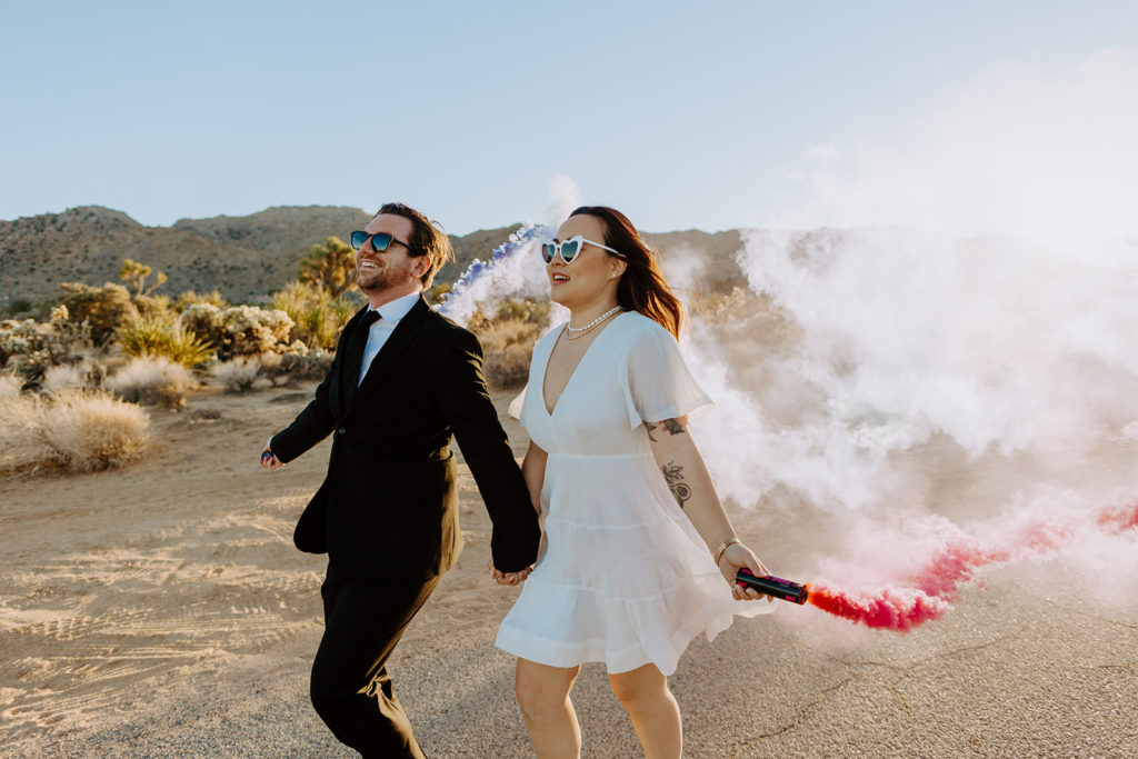 engaged couple use color smoke bombs during engagement photo session in Palm Spring desert 