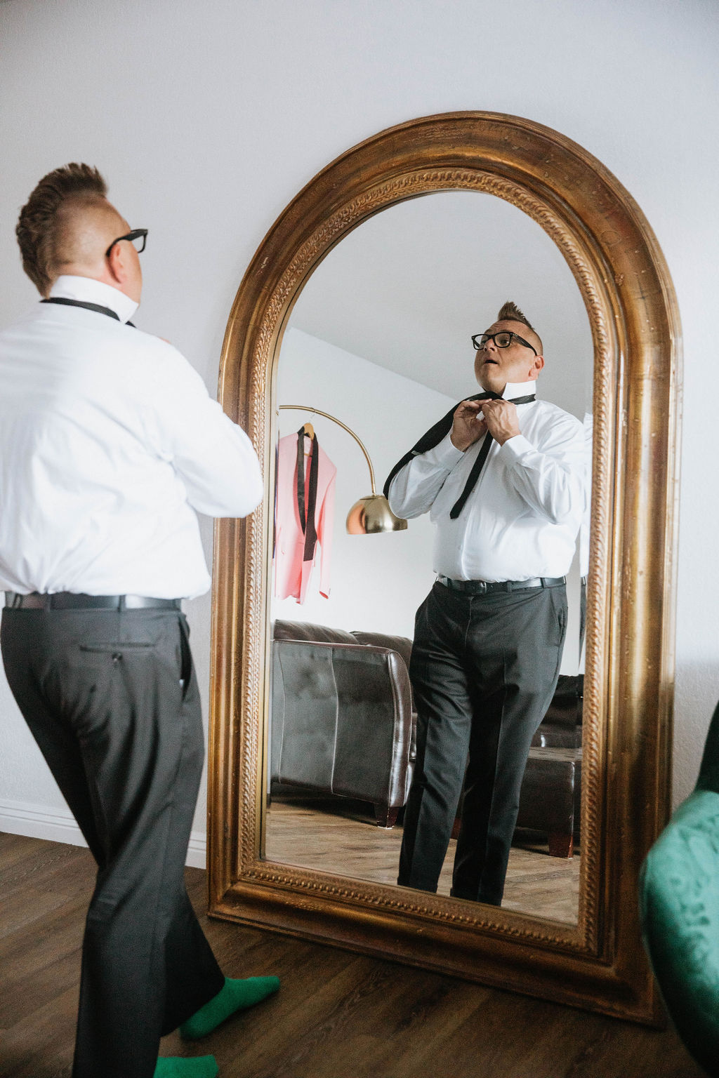 groom in mirror tying his black tie 