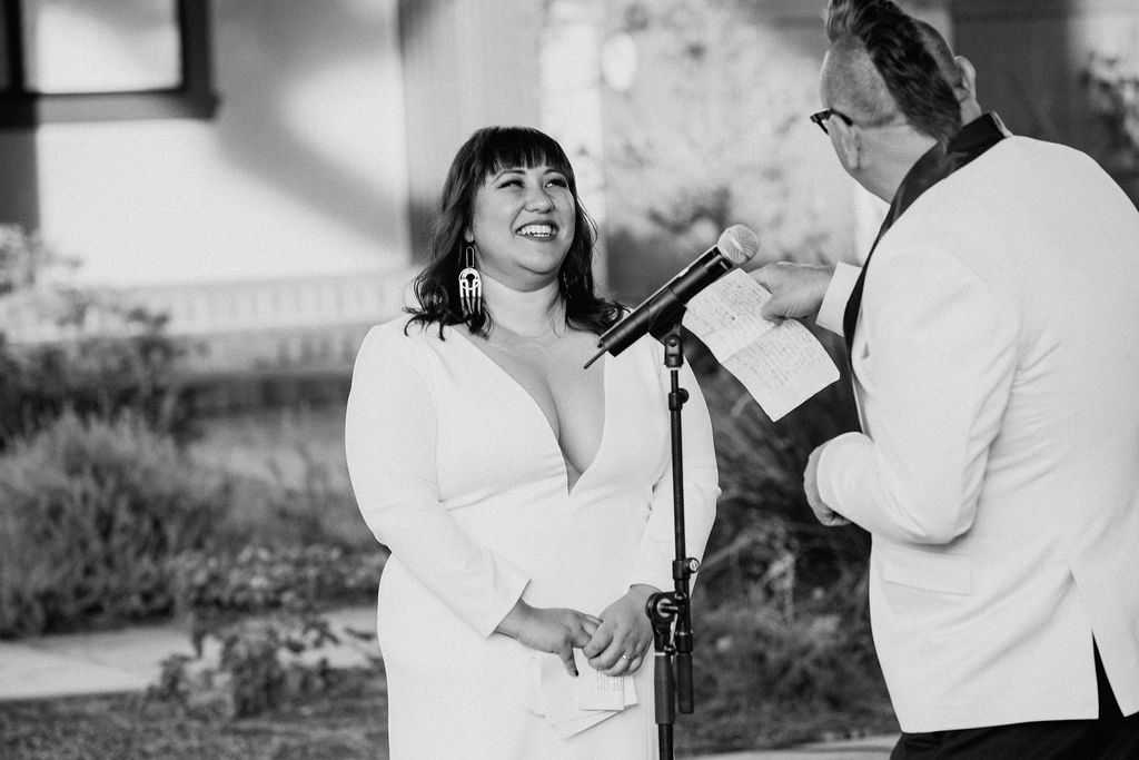 groom reading vows and bride laughing during wedding ceremony