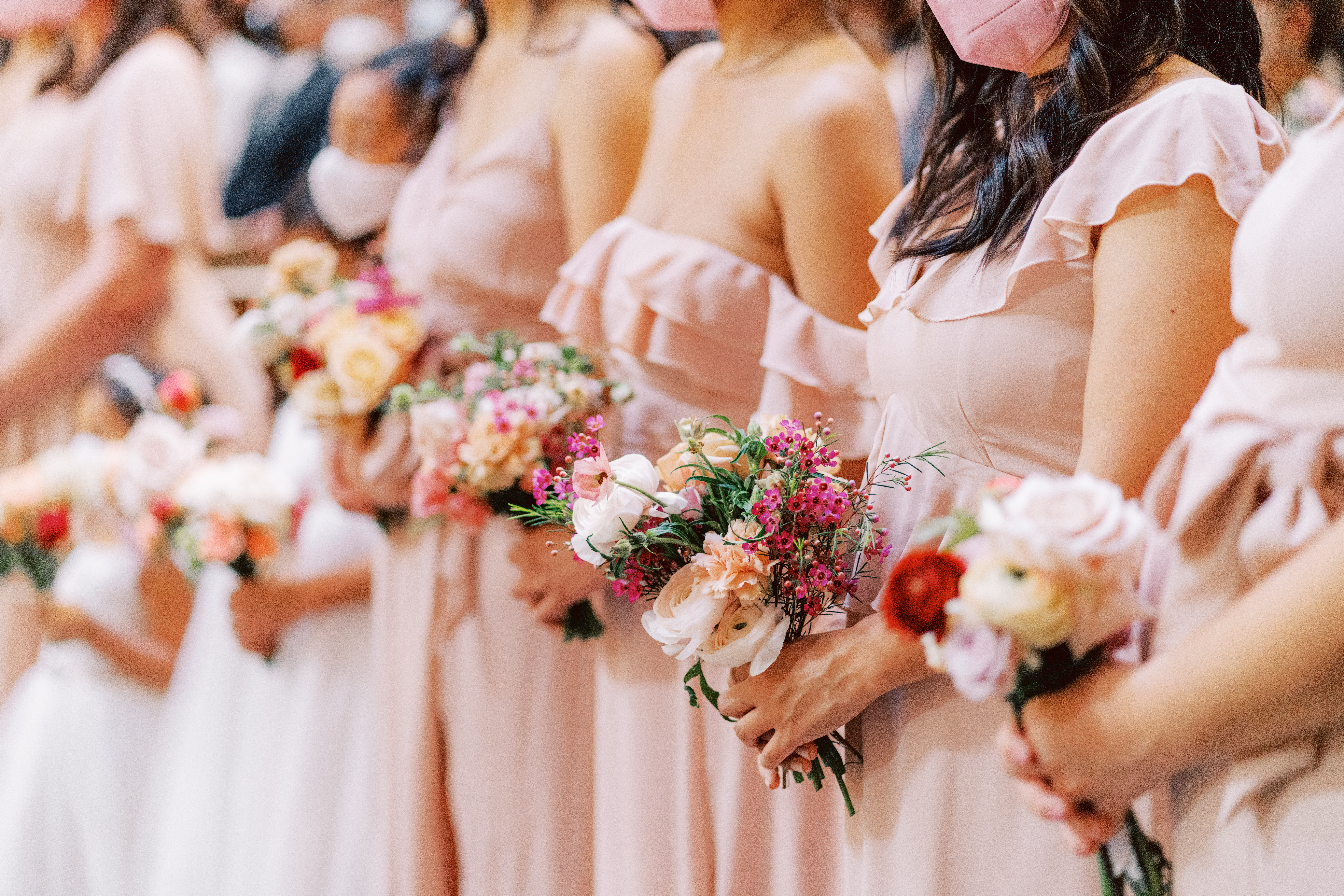 bridesmaids with mismatching light peach dresses and bright floral bouquets
