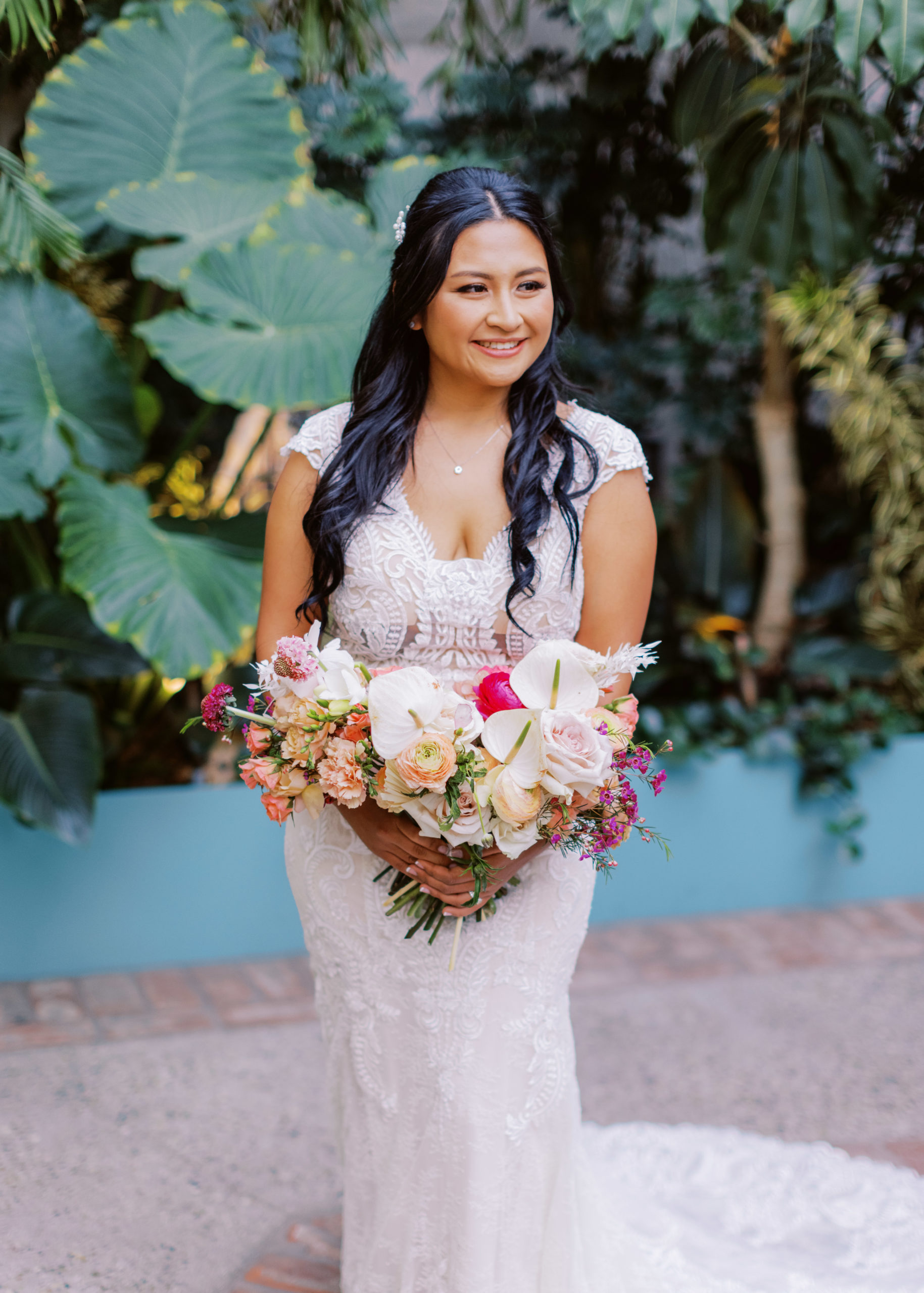 bride in lace dress with bright tropical bouquet poses during cocktail hour at The Valentine DTLA 