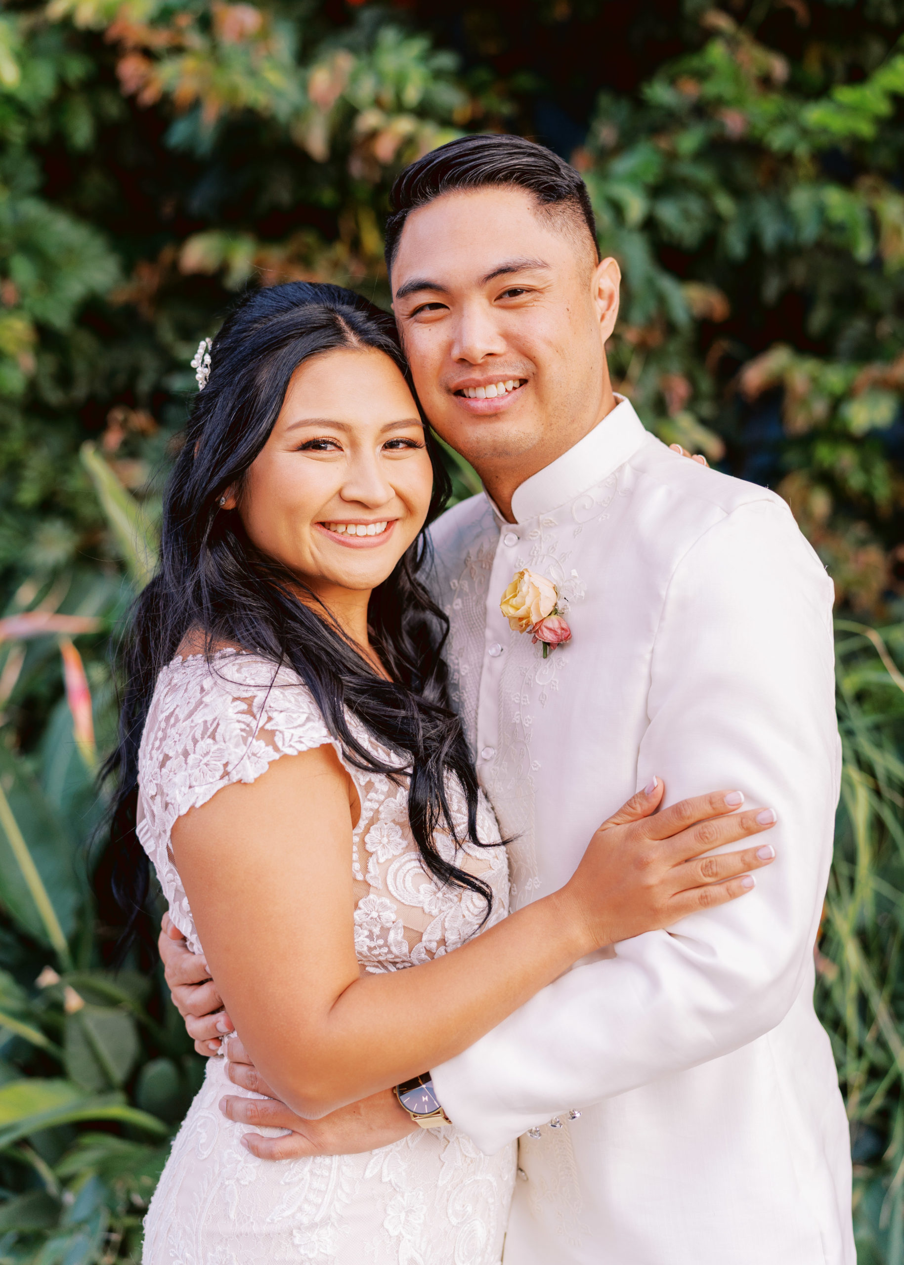 bride and groom pose in front of greenery in DTLA