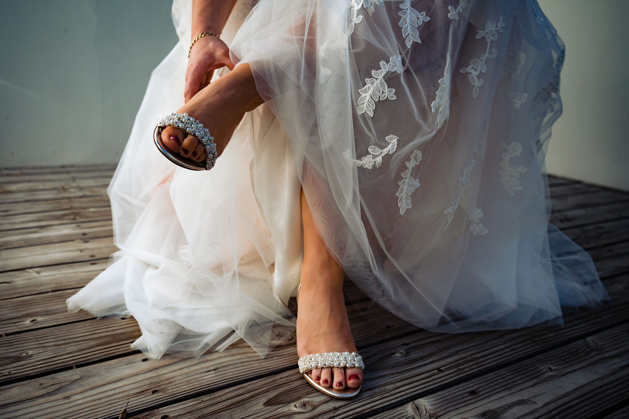 bride putting on heels with pearl embellishment on strap