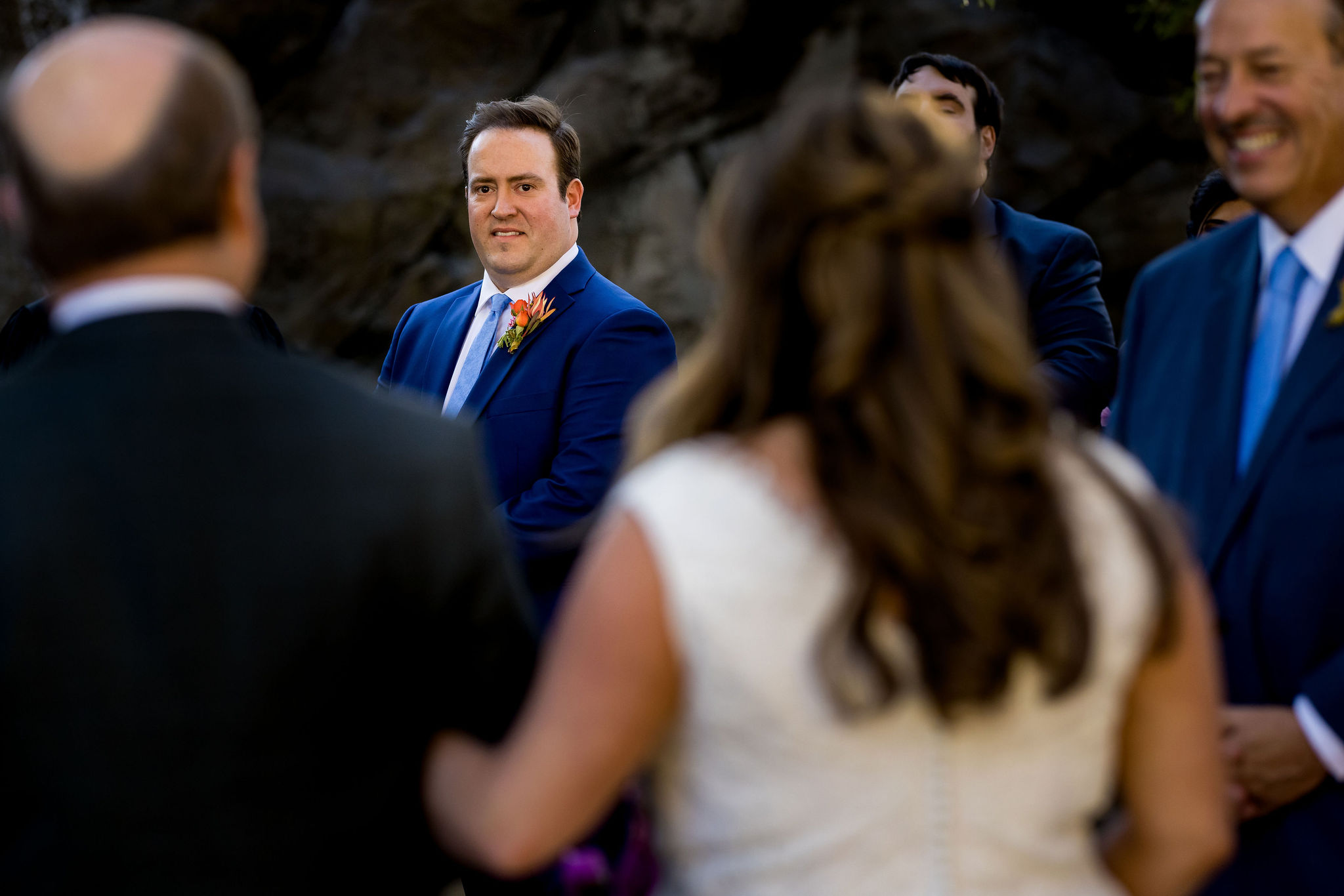 groom in bright blue suit watches bride walking down the aisle