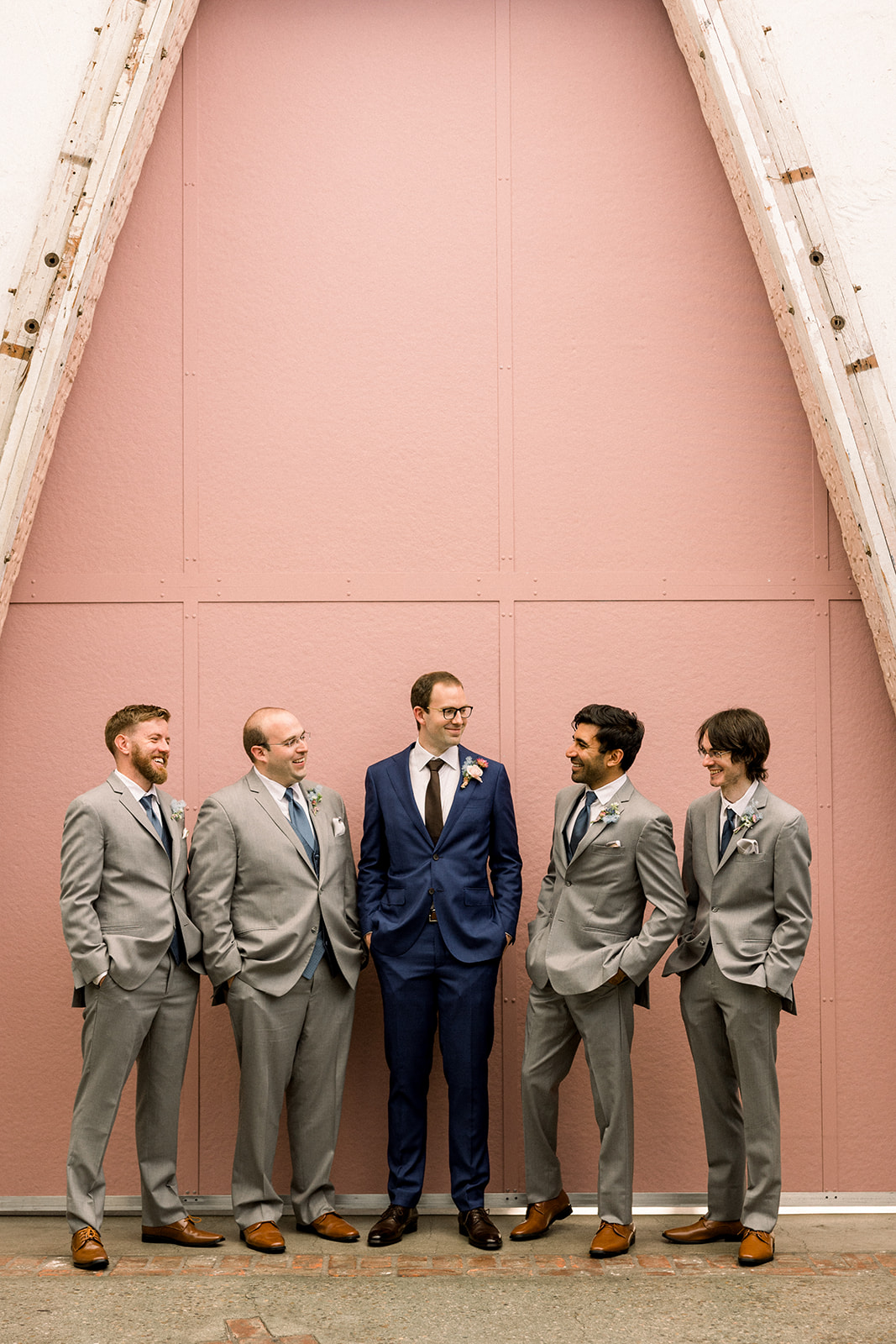 groom in navy suit and black tie stands with groomsmen in grey suits and blue ties at The Grassroom DTLA