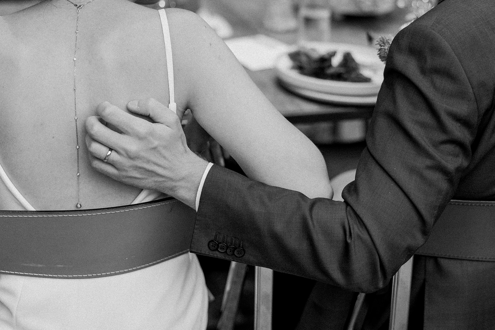 black white photo of groom with hand on brides back during wedding reception