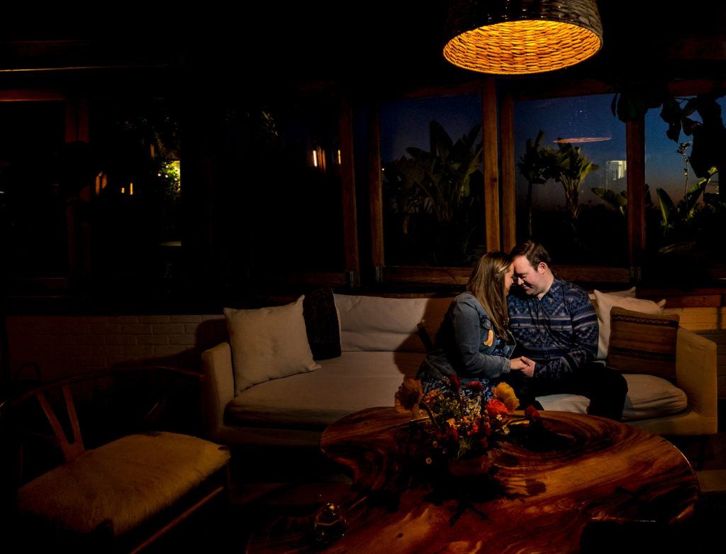 bride and groom sit with their foreheads touching while on couch in lounge area of Calamigos Guest Ranch during their rehearsal dinner