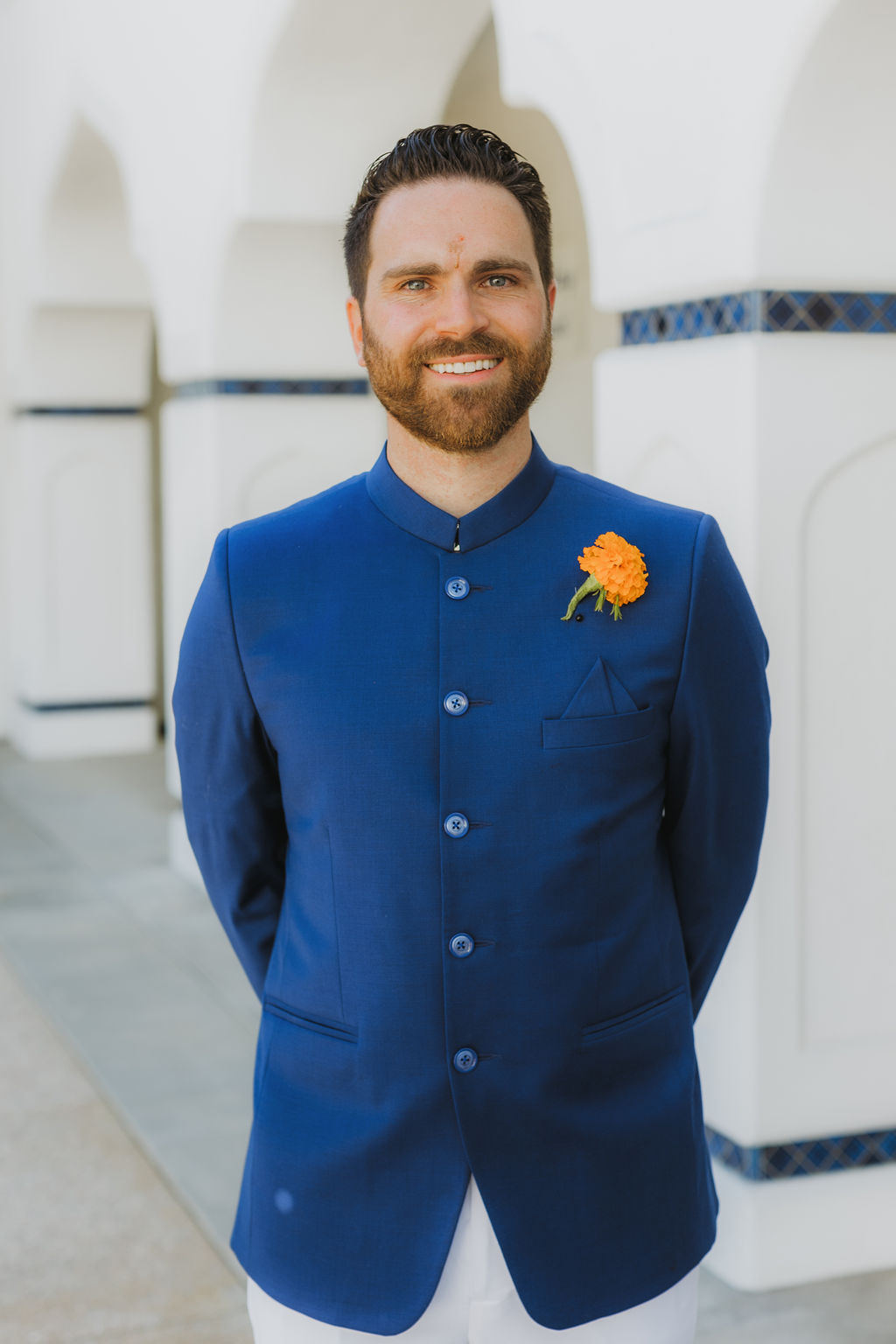 groom in cobalt blue suit wearing marigold boutonniere take portrait photos at Lake Shrine Temple in Malibu
