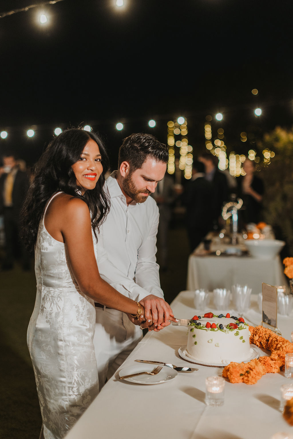 bride in white reception dress cuts cake with groom at Saddlerock Ranch