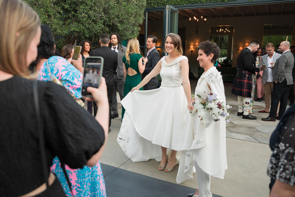 two brides wearing coordinating bridal stand for photos with friends and family after wedding ceremony at The Fig House