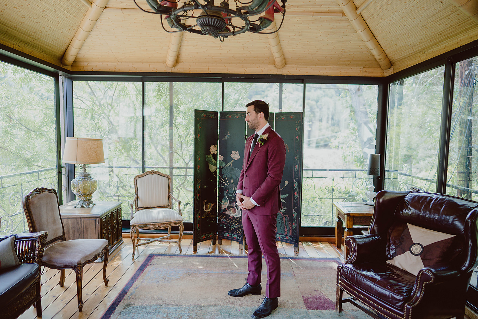 groom in maroon suit and black tie waits for first look with bride before wedding at The Houdini Estate