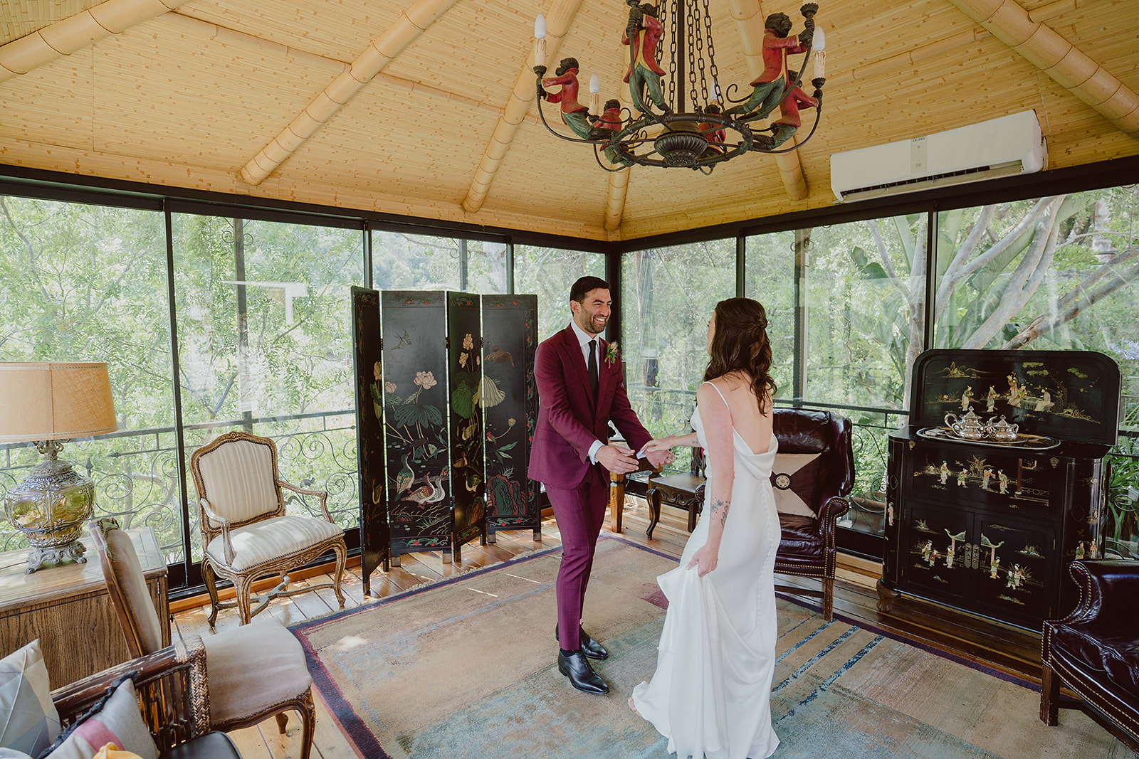 bride in minimalist silk wedding dress does first look with groom in burgundy suit and black tie for their magical wedding at The Houdini Estate in Hollywood