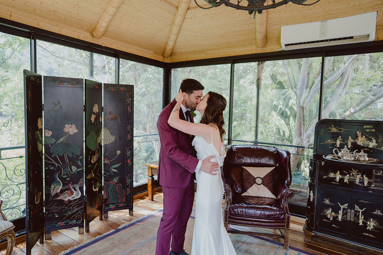 bride in minimalist silk wedding dress does first look with groom in burgundy suit and black tie for their magical wedding at The Houdini Estate in Hollywood