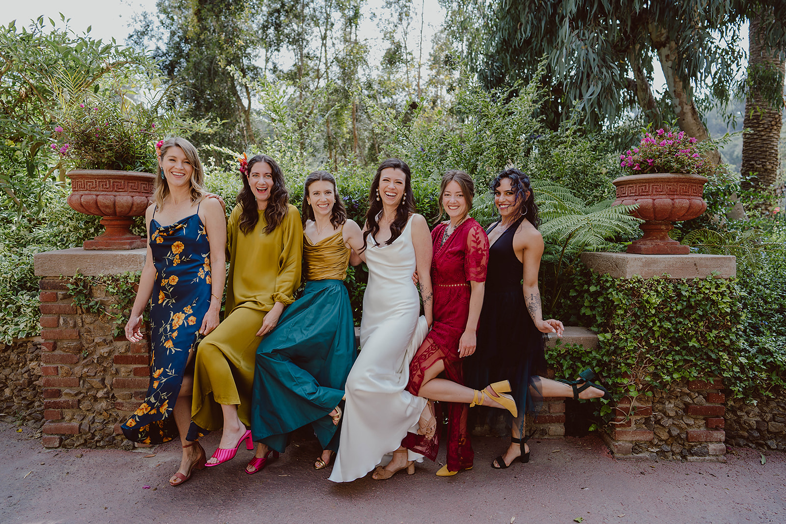 minimalist bride in silk wedding dress stands with bridesmaids in colorful mix matched dresses