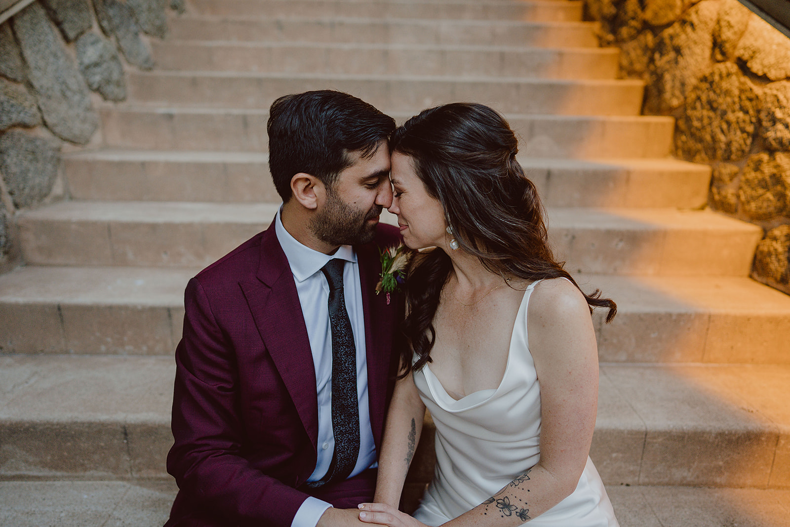 minimalist bride in silk wedding dress with groom in burgundy suit portrait shots