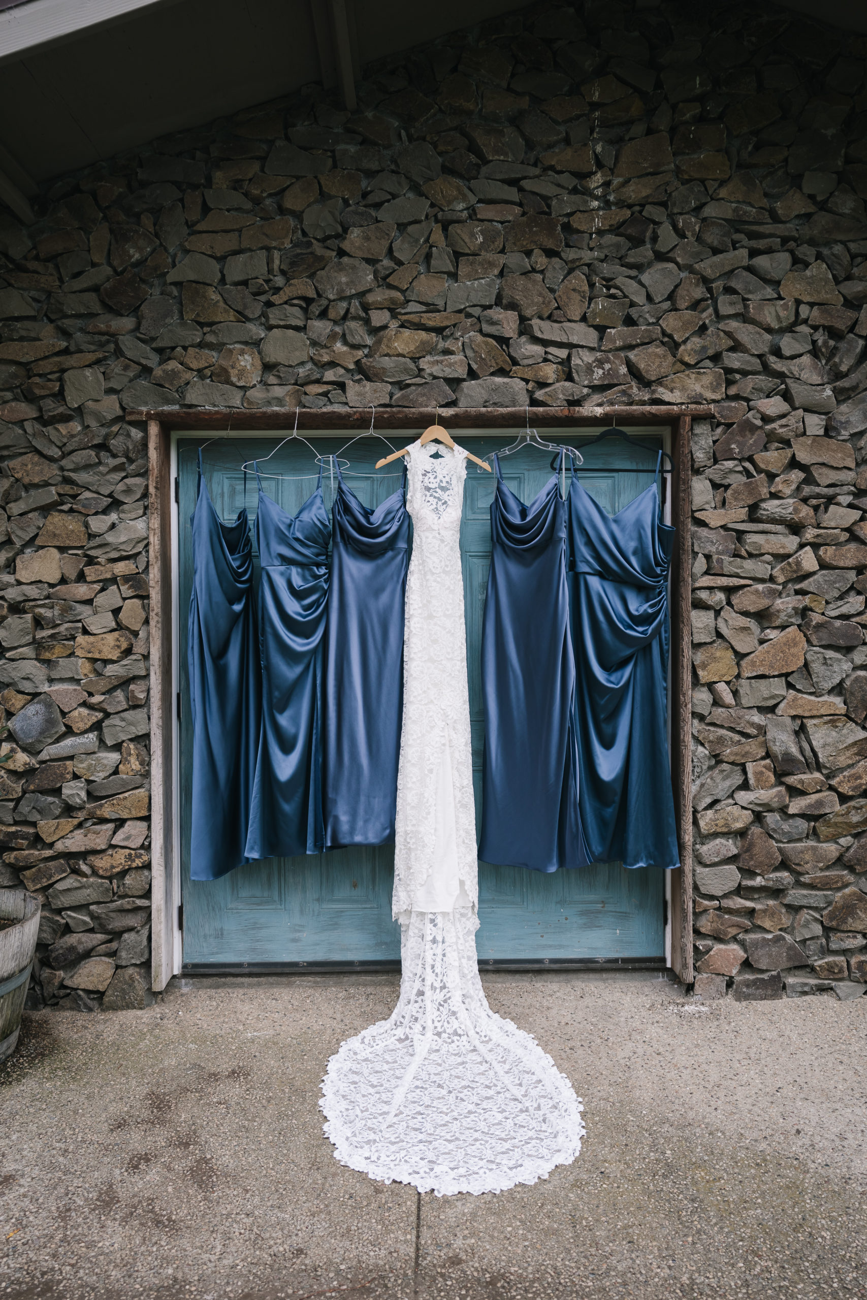 bride in high neckline lace wedding dress on a hanger with dark blue satin bridesmaid dresses