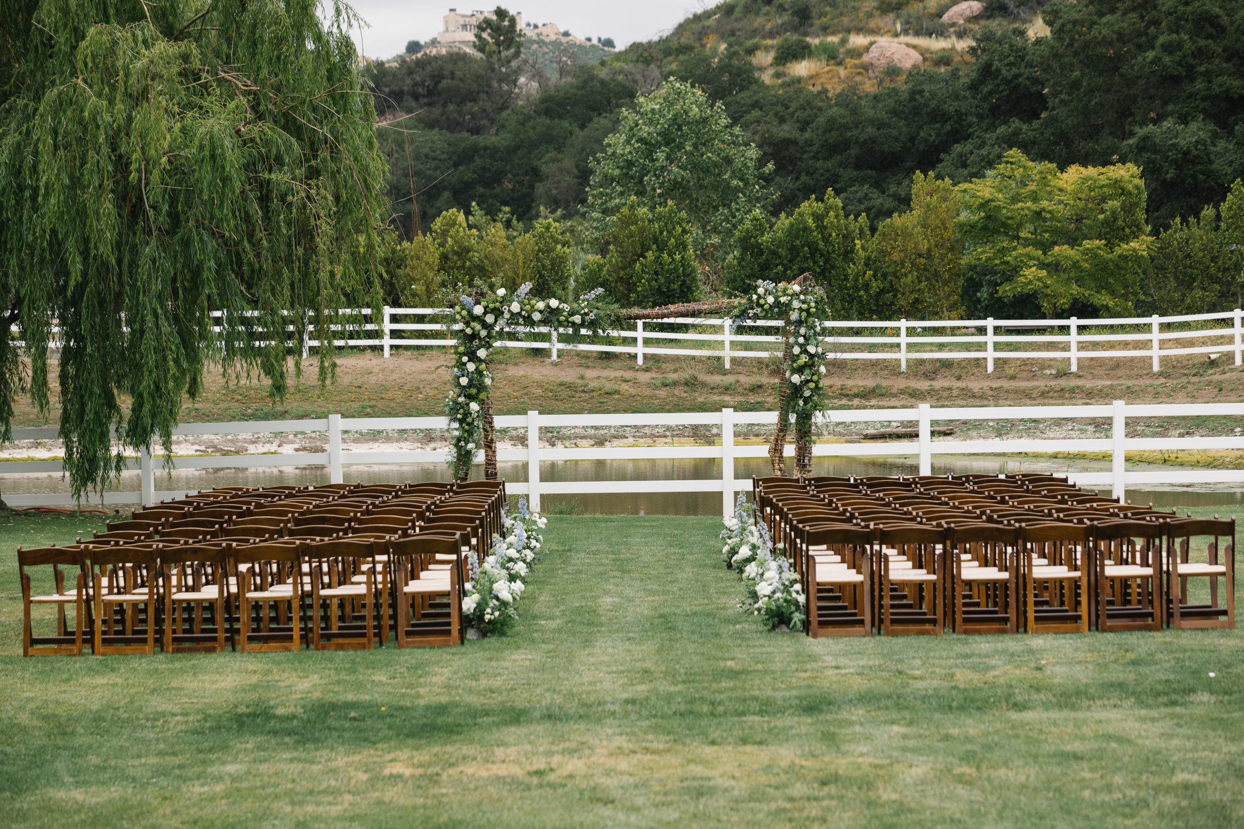 wedding ceremony at Saddlerock Ranch with wooden chairs and white and blue flowers