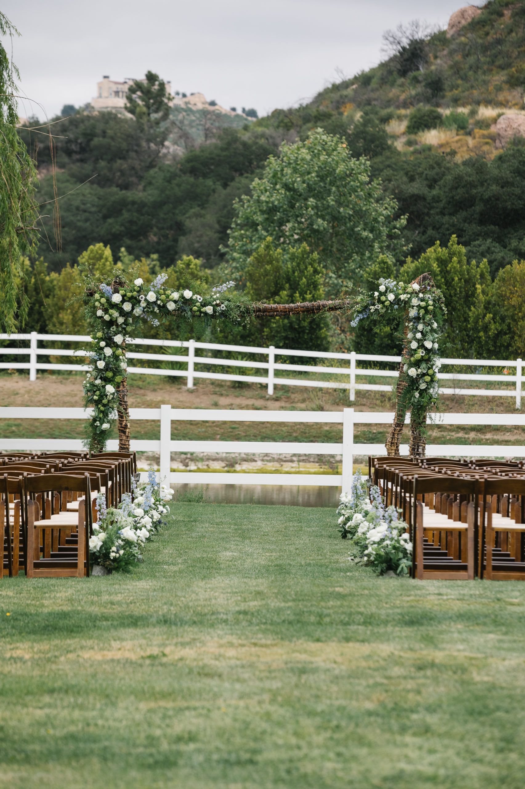wedding ceremony at Saddlerock Ranch with wooden chairs and white and blue flowers
