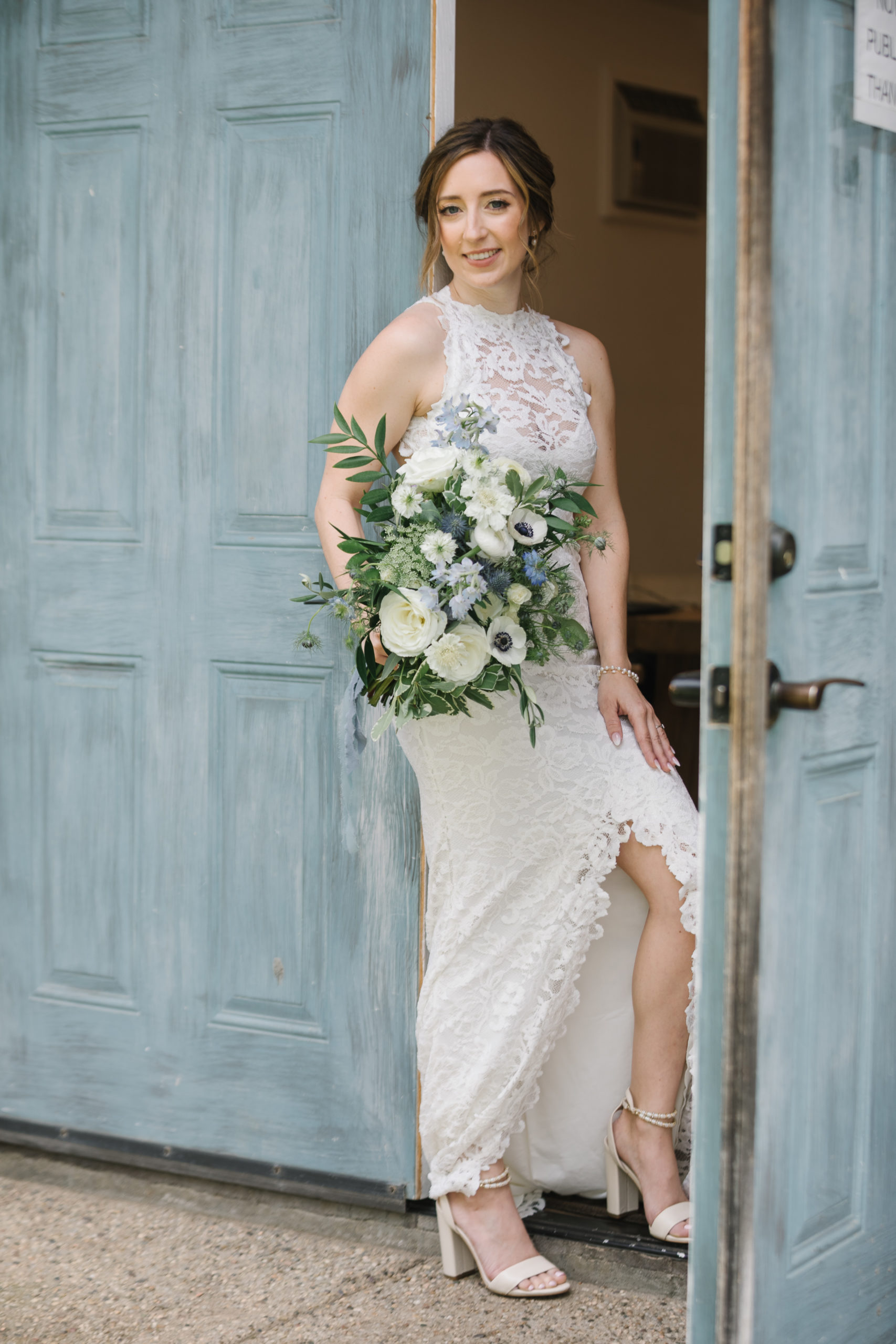 bride in high neckline lace wedding dress and white and blue bridal bouquet 