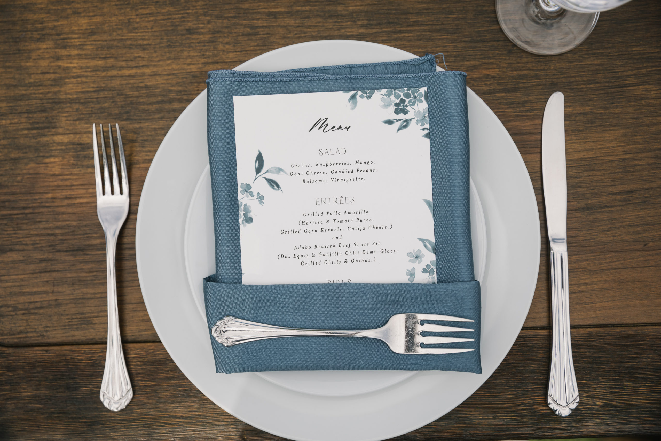 menu card tucked into dark blue napkin on white plate