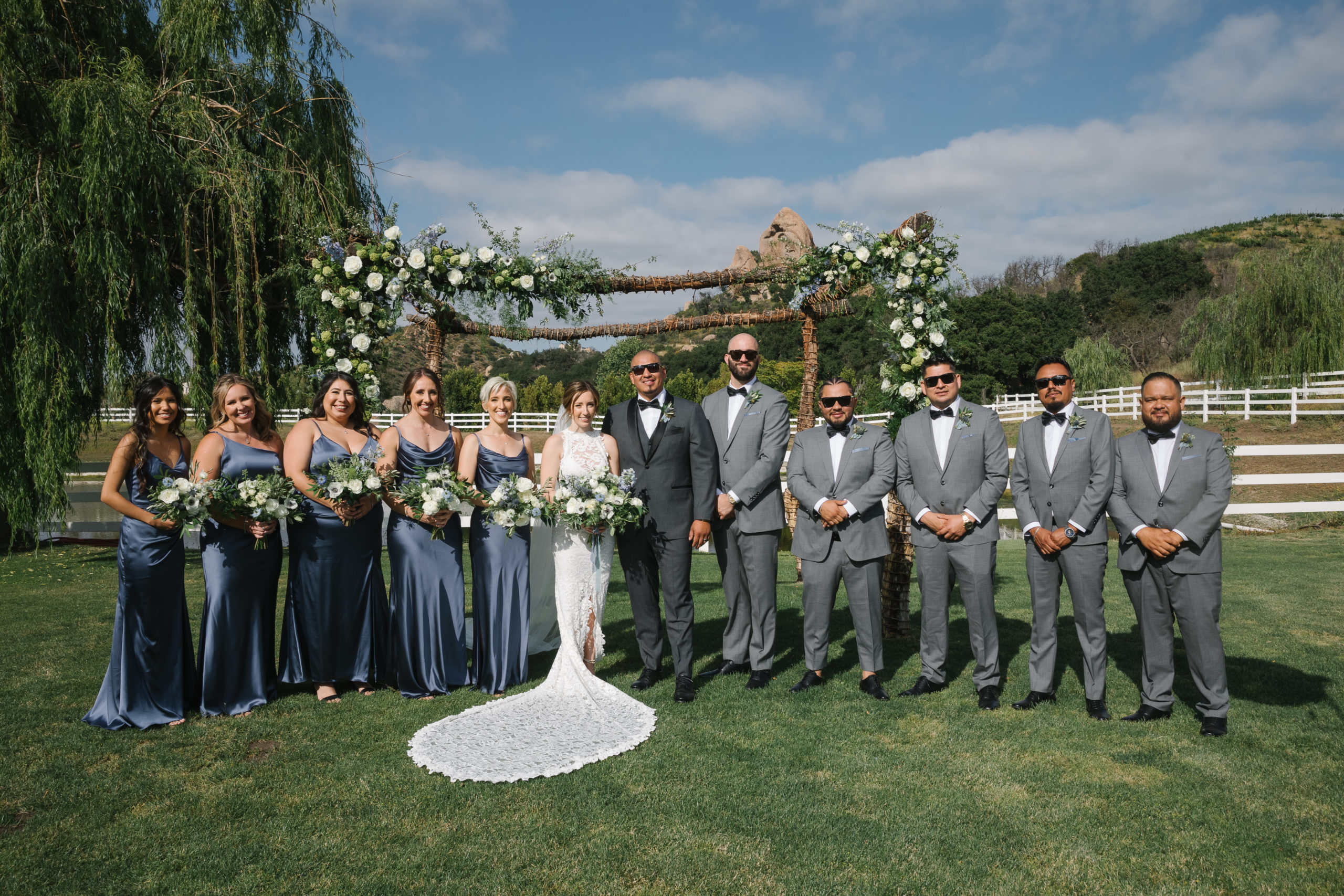 wedding party portrait shot with bride in high neckline open back lace wedding dress and groom in dark grey suit and black bowtie at Saddlerock Ranch