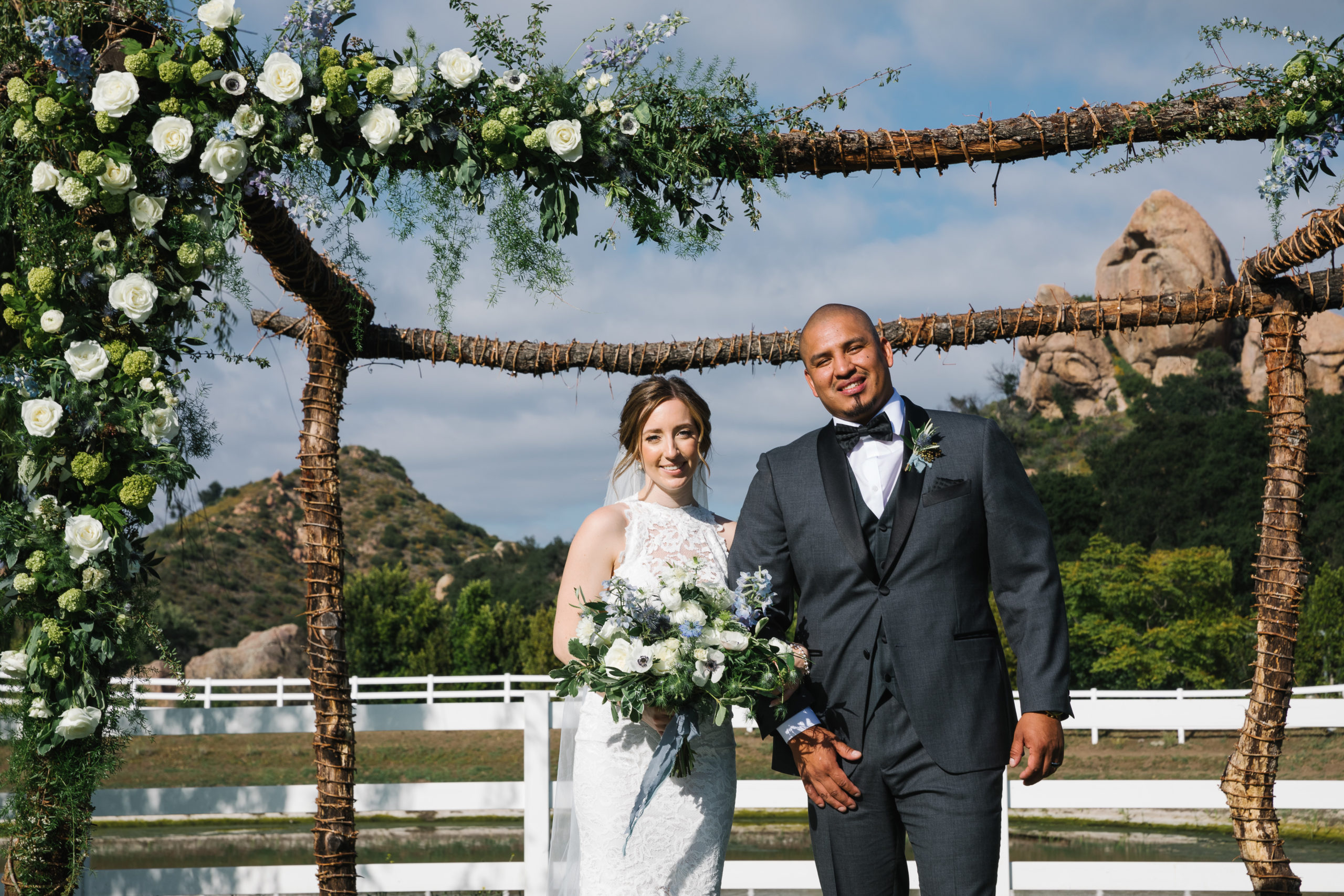 romantic portrait shot with bride in high neckline open back lace wedding dress and groom in dark grey suit and black bowtie at Saddlerock Ranch