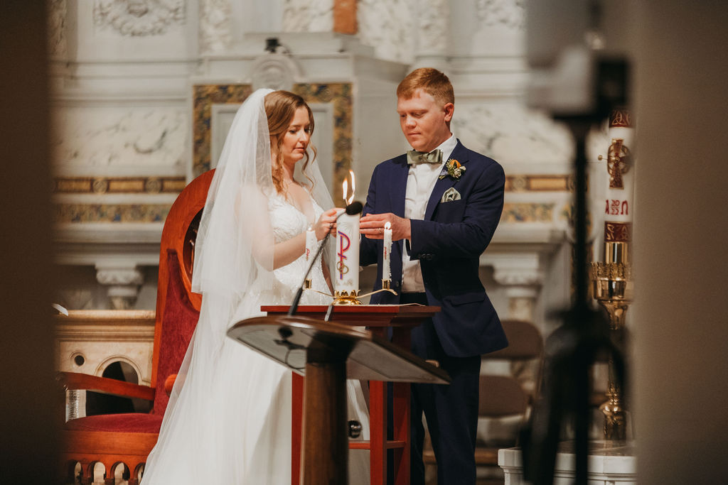 bride and groom lighting unity candle during wedding ceremony at Saint Monica Catholic Church