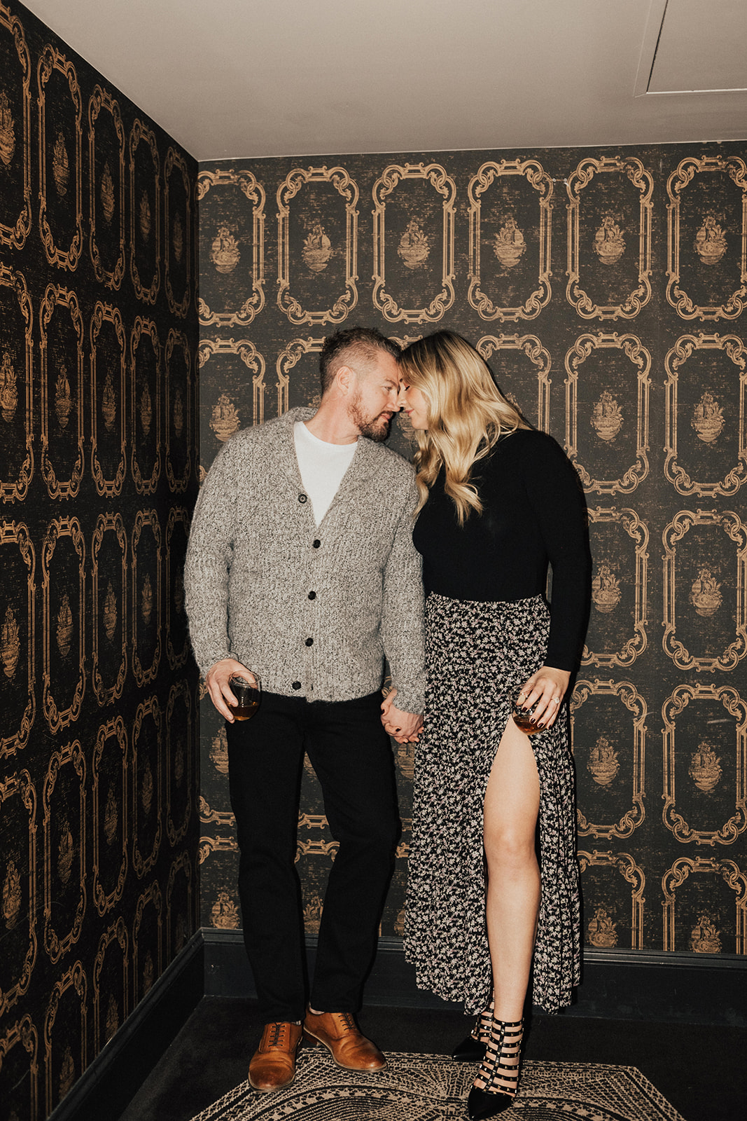 couple holding hands in Art Deco inspired hotel hallway during engagement photo shoot