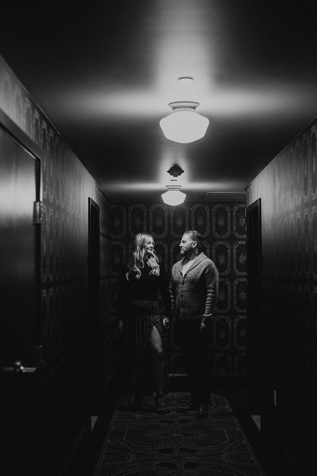 couple holding hands in Art Deco inspired hotel hallway during engagement photo shoot