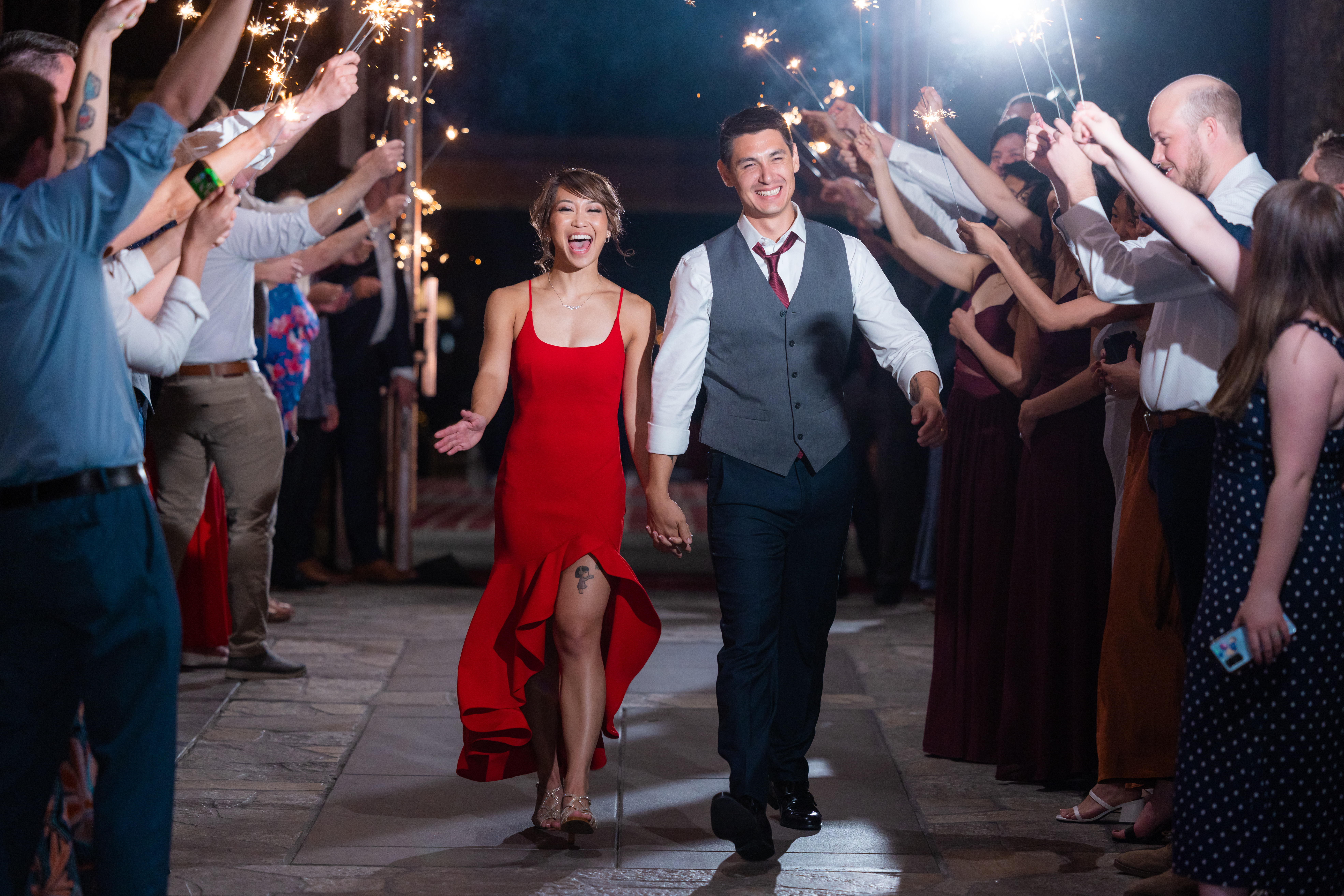 bride in red reception dress and groom have grand exit with sparklers