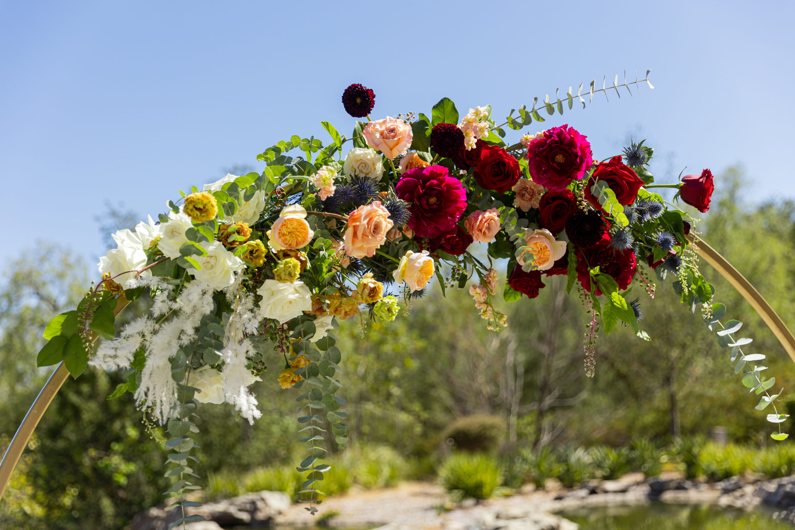 gold circle wedding ceremony arch with jewel toned florals