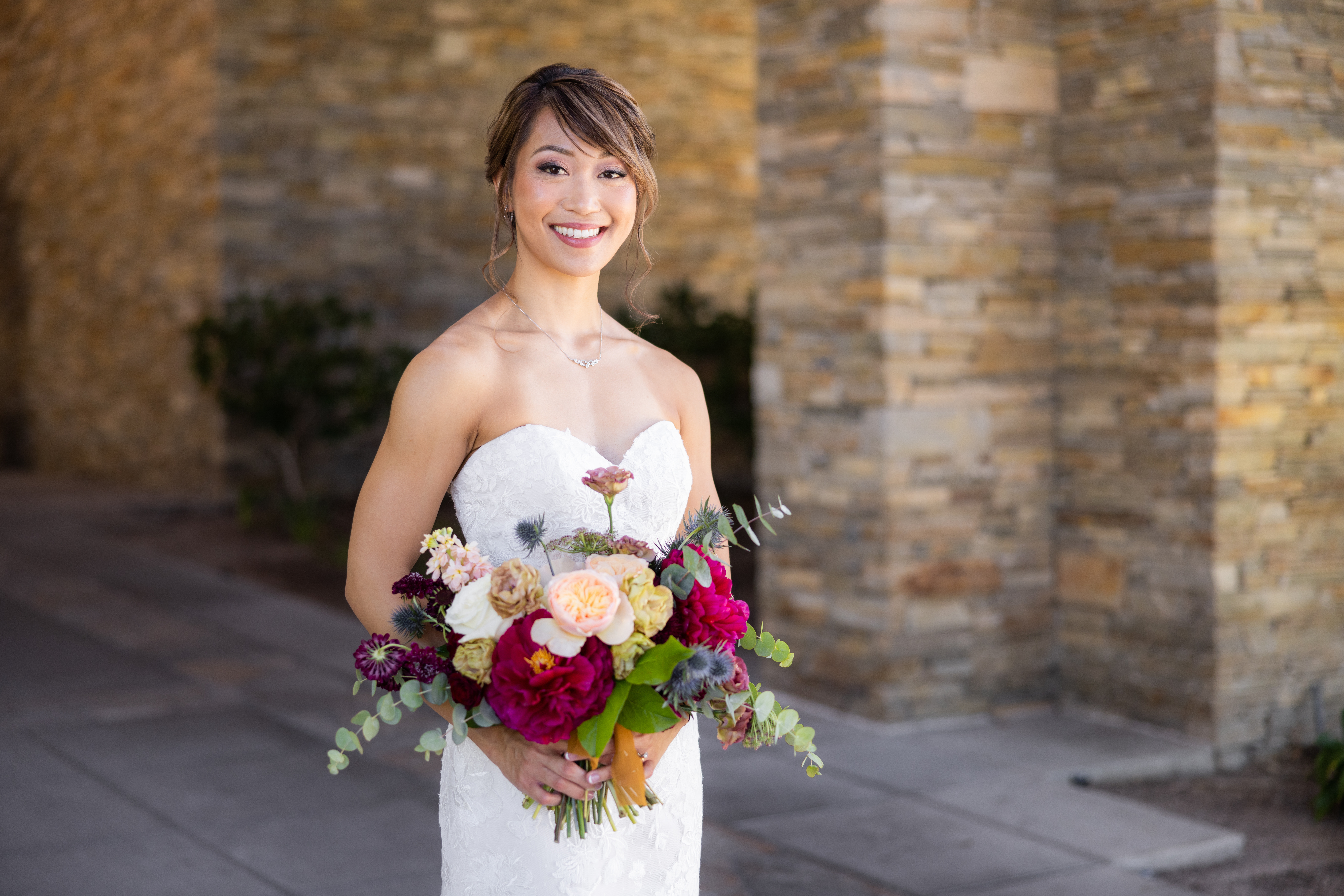 bride in strapless lace wedding dress and jewel toned bouquet