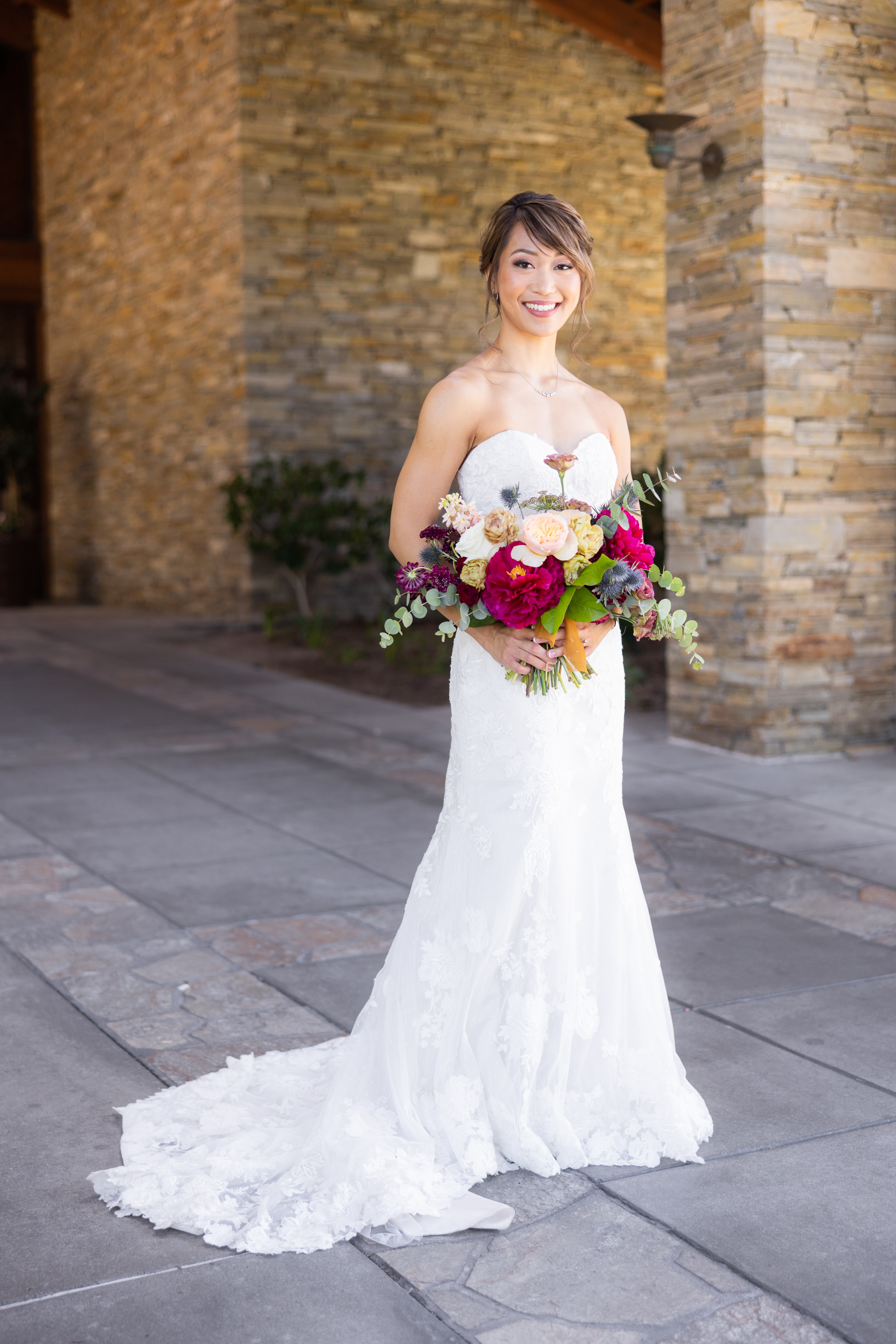bride in strapless lace wedding dress and jewel toned bouquet
